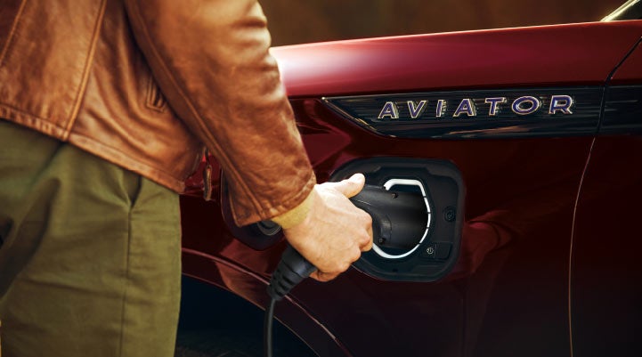 A hand is shown plugging in the charger into the charging port of a 2021 Lincoln Aviator | Vista Lincoln Woodland Hills in Woodland Hills CA