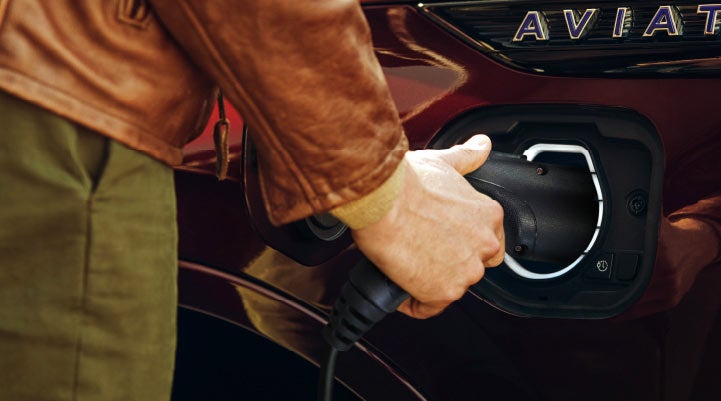 A hand is shown plugging in the charger into the charging port of a 2021 Lincoln Aviator | Vista Lincoln Woodland Hills in Woodland Hills CA