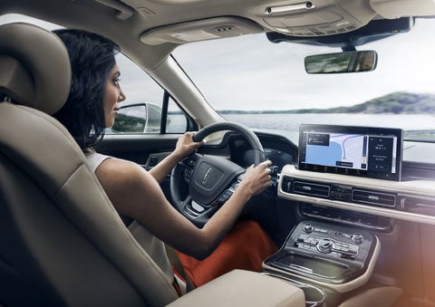 A person is shown driving a Lincoln Nautilus® SUV while using the available Connected Built-In Navigation System.