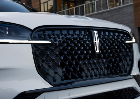 The black grille of a white 2025 Lincoln Aviator® SUV is shown with its fog lights on. | Vista Lincoln Woodland Hills in Woodland Hills CA