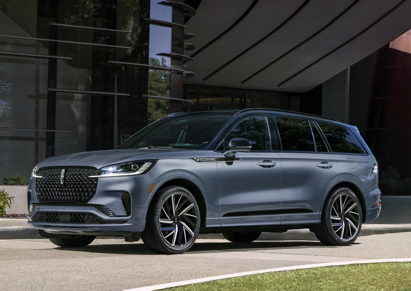 A gray 2025 Lincoln Aviator® SUV is parked outside a modern building showcasing the driver’s side of the vehicle. | Vista Lincoln Woodland Hills in Woodland Hills CA