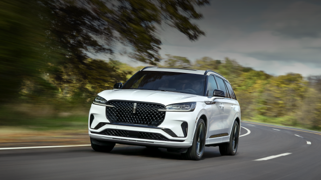 A white 2025 Lincoln Aviator® SUV is being driven down a road lined with trees. | Vista Lincoln Woodland Hills in Woodland Hills CA