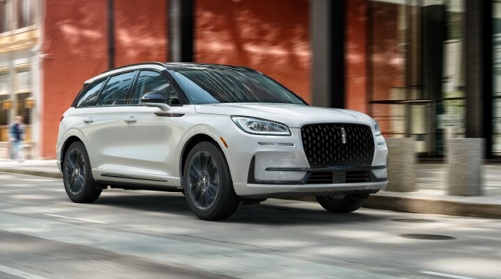 A white 2025 Lincoln Corsair® SUV with the Jet Appearance Package is being driven through a city.| Vista Lincoln Woodland Hills in Woodland Hills CA