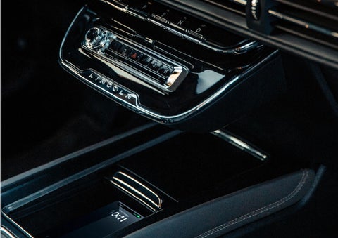 A smartphone is is being placed on the wireless charging pad in the front center console cubby. | Vista Lincoln Woodland Hills in Woodland Hills CA