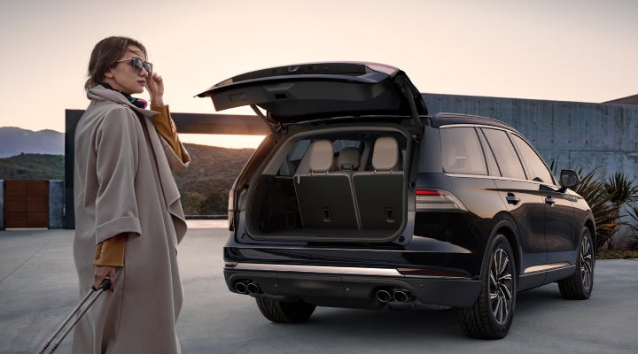 A woman approaches a 2026 Lincoln Aviator® SUV with its rear liftgate open. | Vista Lincoln Woodland Hills in Woodland Hills CA