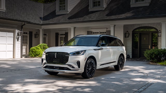A white 2026 Lincoln Aviator® SUV is parked in the driveway of a luxury home. | Vista Lincoln Woodland Hills in Woodland Hills CA